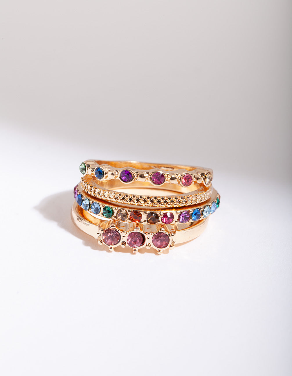 Showcasing gold diamante rainbow stacking rings in a 4-pack with statement style featuring purple, blue, and green accents front view