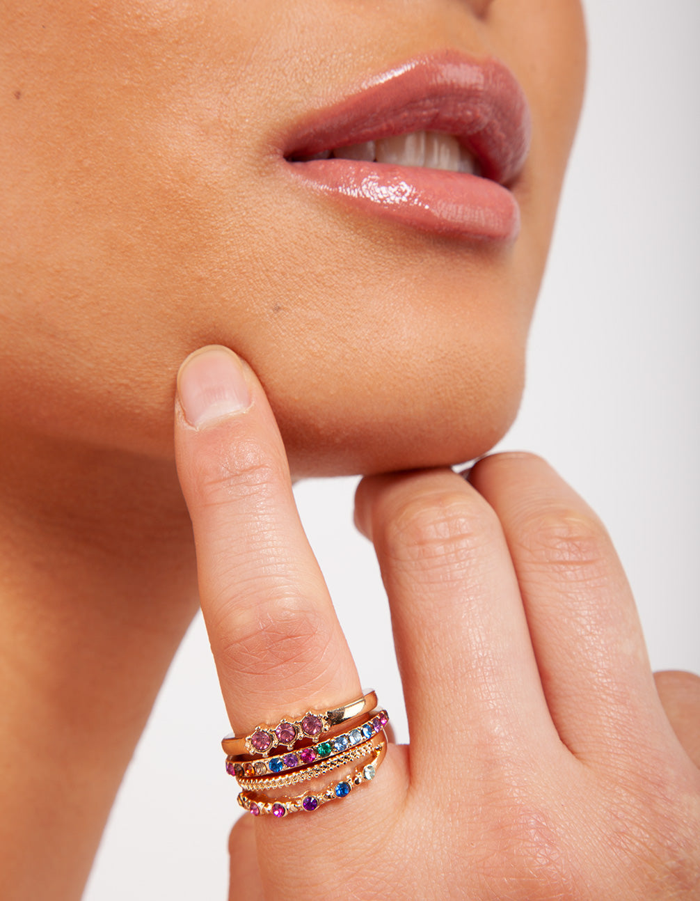 Featuring gold diamante rainbow stacking rings in a 4-pack with statement style showcasing purple, blue, and green accents on finger view