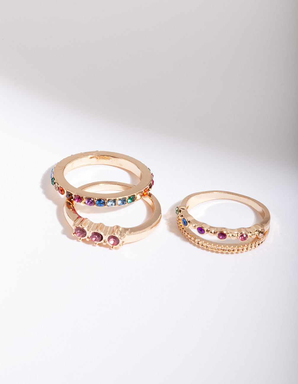 Crafted from gold with diamante rainbow stacking rings in a 4-pack featuring statement style and purple, blue, green accents side detail view