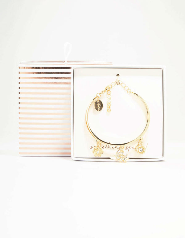 Showcasing a wrist cuff featuring floral charm details in gold front view