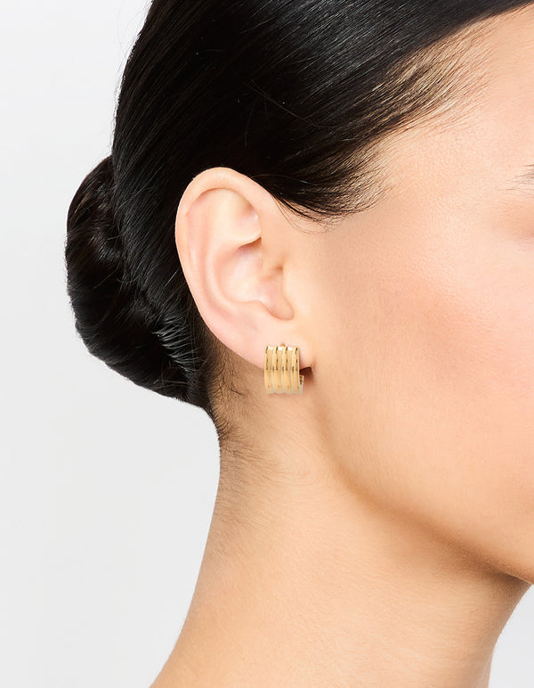 Crafted from waterproof gold plated stainless steel, ribbed huggie earrings on ear view