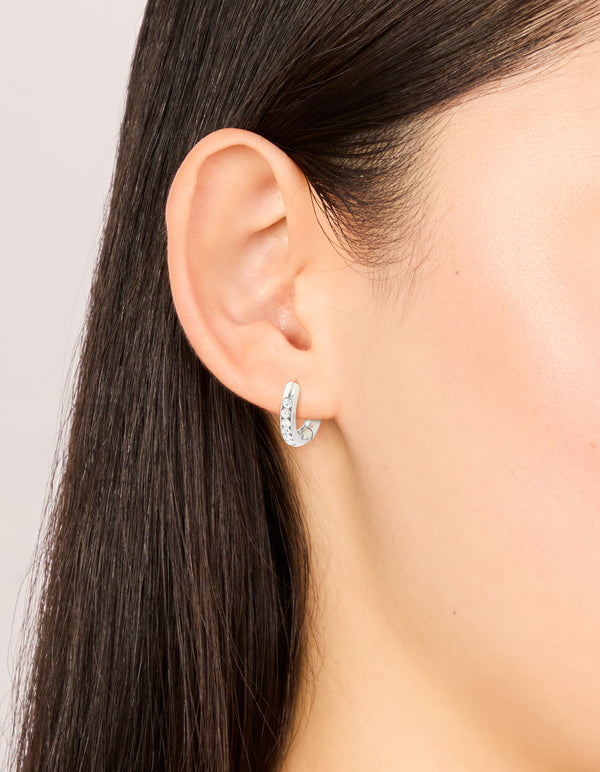 Featuring waterproof stainless steel cubic zirconia round clicker huggie earrings in silver on ear view