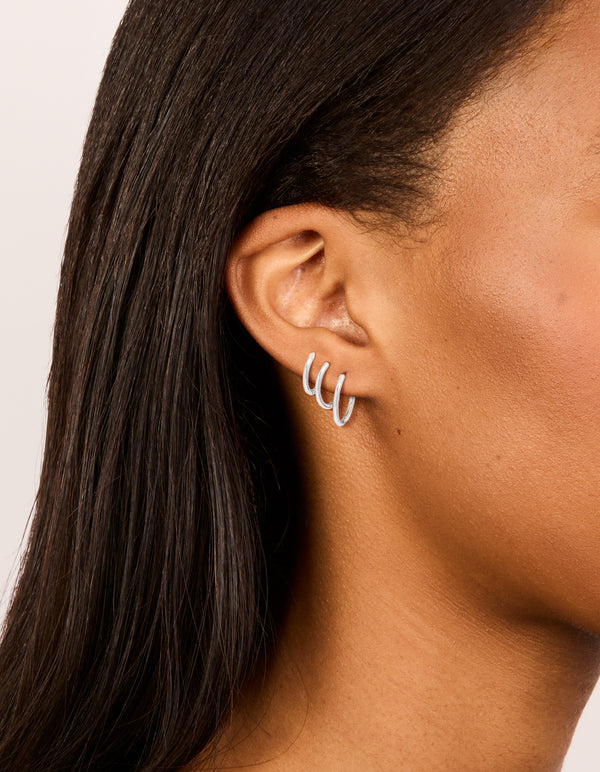 Introducing waterproof stainless steel thin hoop earrings in a 3-pack with silver finish on ear view