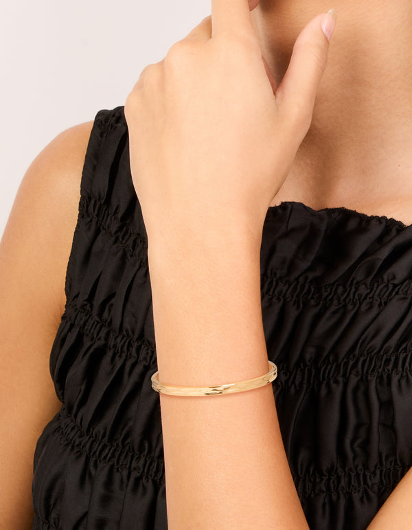 Showcasing a waterproof hammered hinged bangle crafted from stainless steel with gold plating on wrist view