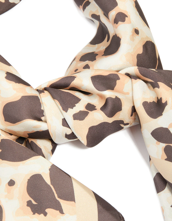 Presenting a brown fabric scarf with animal print in tan and rosy brown detail view