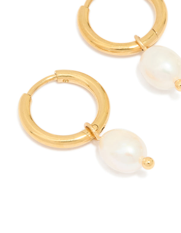 Displayed are waterproof gold plated stainless steel mini pearl drop huggie earrings in ivory close up view