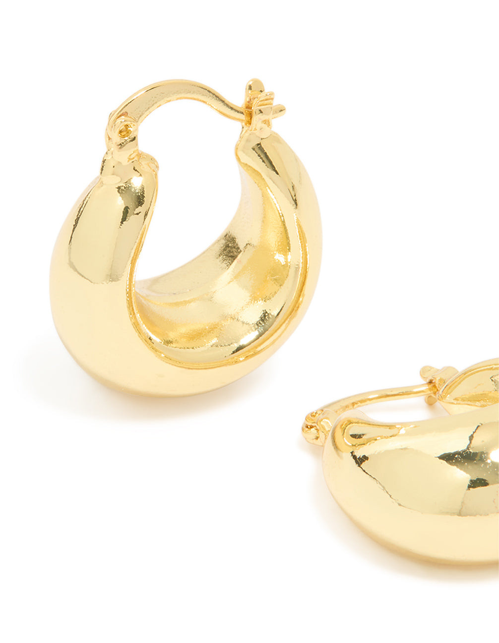 Highlighting gold plated brass medium huggie earrings with closure mechanism close up view
