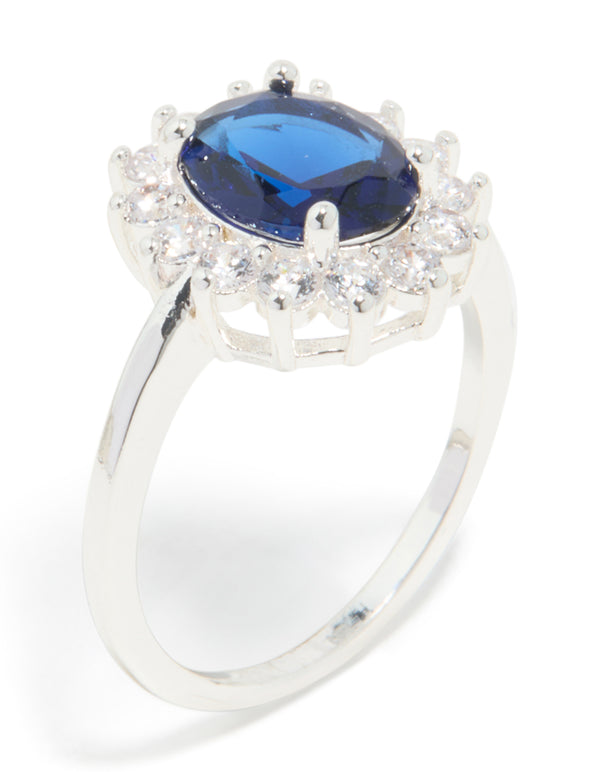 Designed with plated material this statement ring showcases cubic zirconia border surrounding an oval cut center stone in deep blue close up view