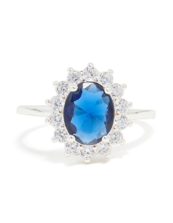 Showcasing a statement ring crafted from plated material featuring cubic zirconia border surrounding an oval cut center stone in deep blue front view