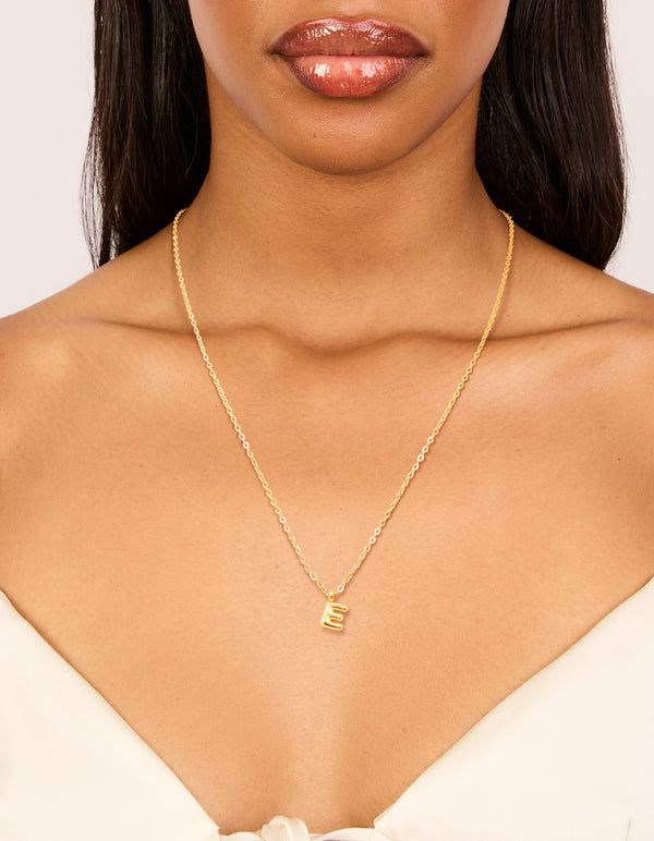 Featuring a waterproof gold plated stainless steel mini bubble letter E pendant initial necklace in dainty style on neck view