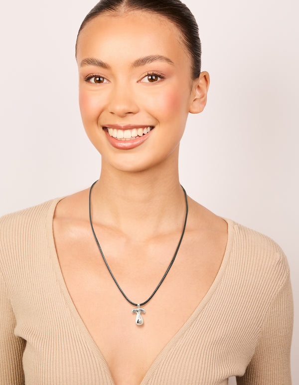 Crafted from waterproof stainless steel, this large bubble letter T initial silver pendant features grey cord necklace on model view