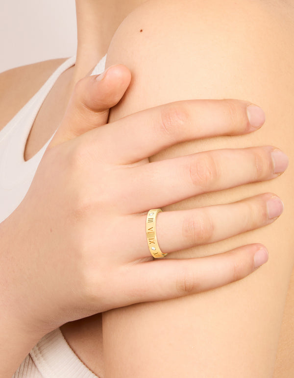 Featuring a waterproof gold plated stainless steel band ring with roman numerals and cubic zirconia accents on finger view