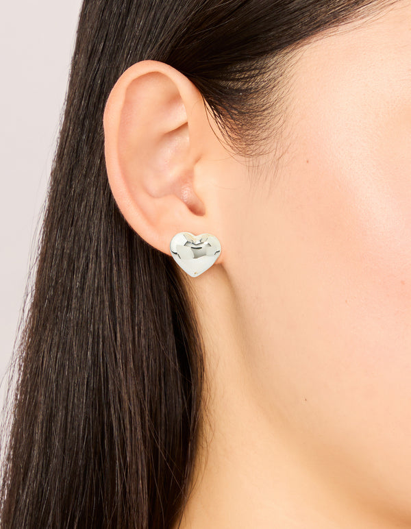Featuring small chunky heart stud earrings in waterproof stainless steel with silver finish on ear view
