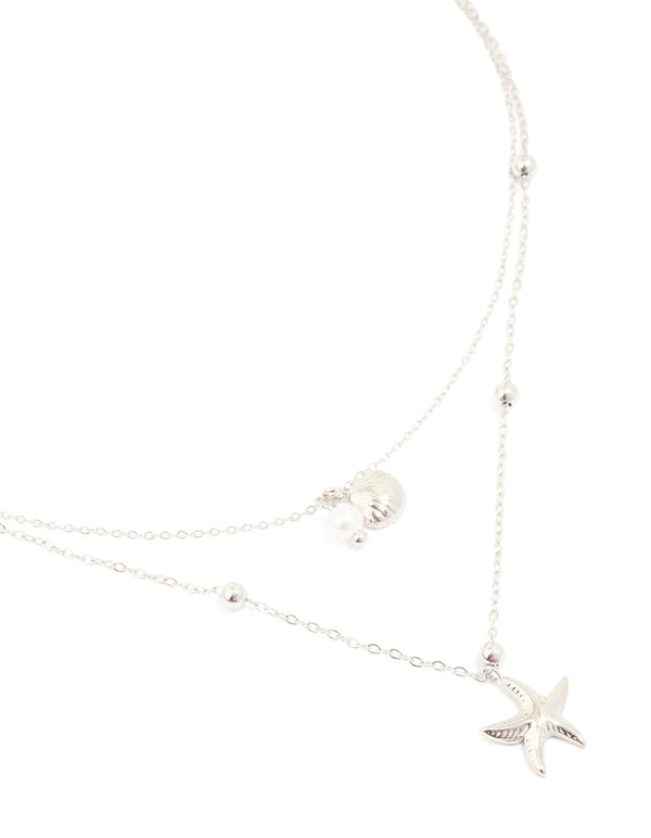 Showcasing a waterproof stainless steel starfish and shell layered necklace with balls, charm and pearl featuring ocean-inspired details in silver close up view
