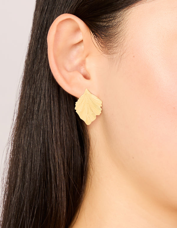 Featuring waterproof gold plated stainless steel textured leaf earrings in a radiant gold shade on ear view