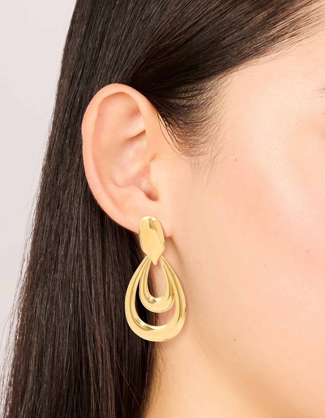 Showcasing waterproof gold plated stainless steel double doorknocker earrings with statement design on ear view