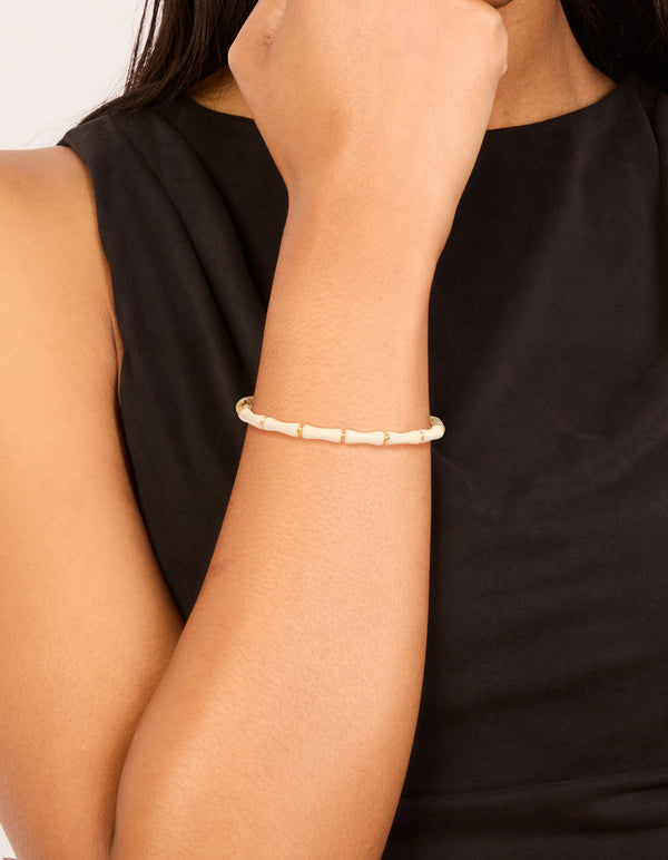 Showcasing a waterproof bamboo white enamel bangle crafted from gold plated stainless steel with ivory accents on wrist view