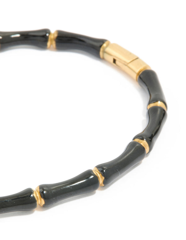 Displaying a waterproof gold plated stainless steel black enamel bamboo bangle with statement design close up view