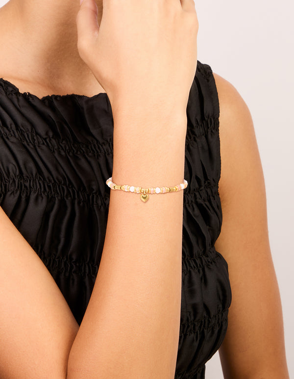Showcasing a waterproof gold plated stainless steel rose quartz semi precious mini heart bracelet with beads, charm, and dainty styling on wrist view