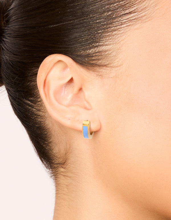 Showcasing small waterproof blue enamel inlay huggie earrings in gold plated stainless steel on ear view