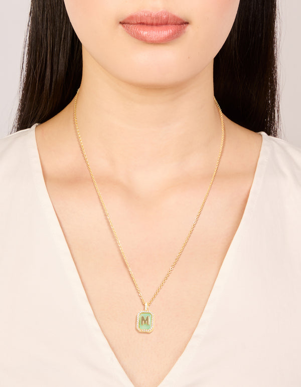 Showcasing a gold plated brass cubic zirconia letter M tag necklace with initials pendant on neck view