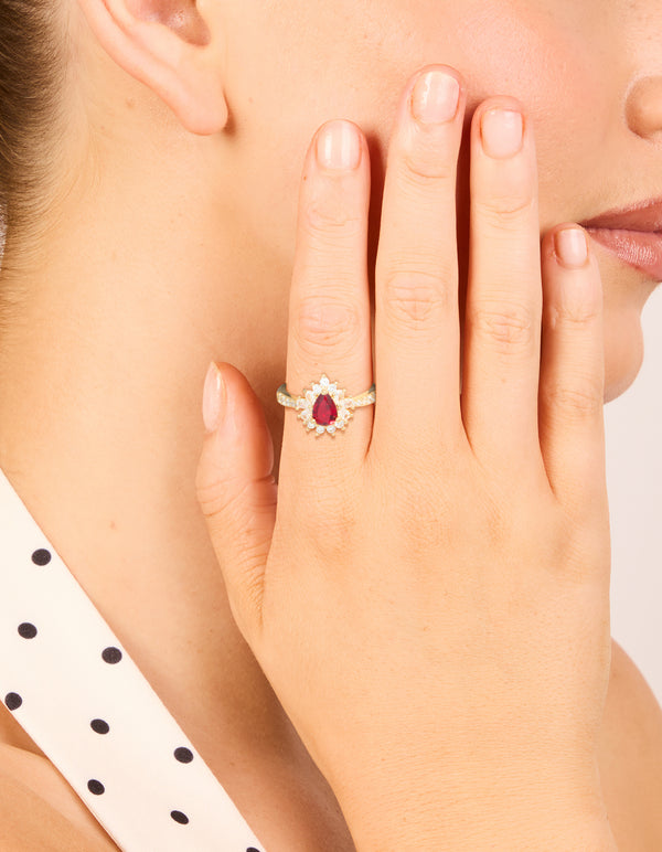 Featuring a gold plated gleaming red cubic zirconia pear ring with crystal and clear stone details on finger view
