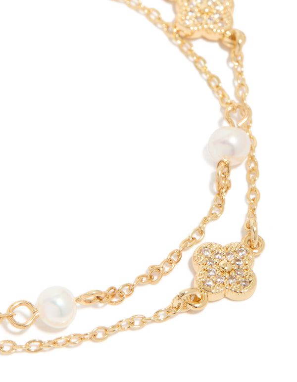 Designed with floral details, this dainty gold plated cubic zirconia and freshwater pearl layered bracelet shown in close up view