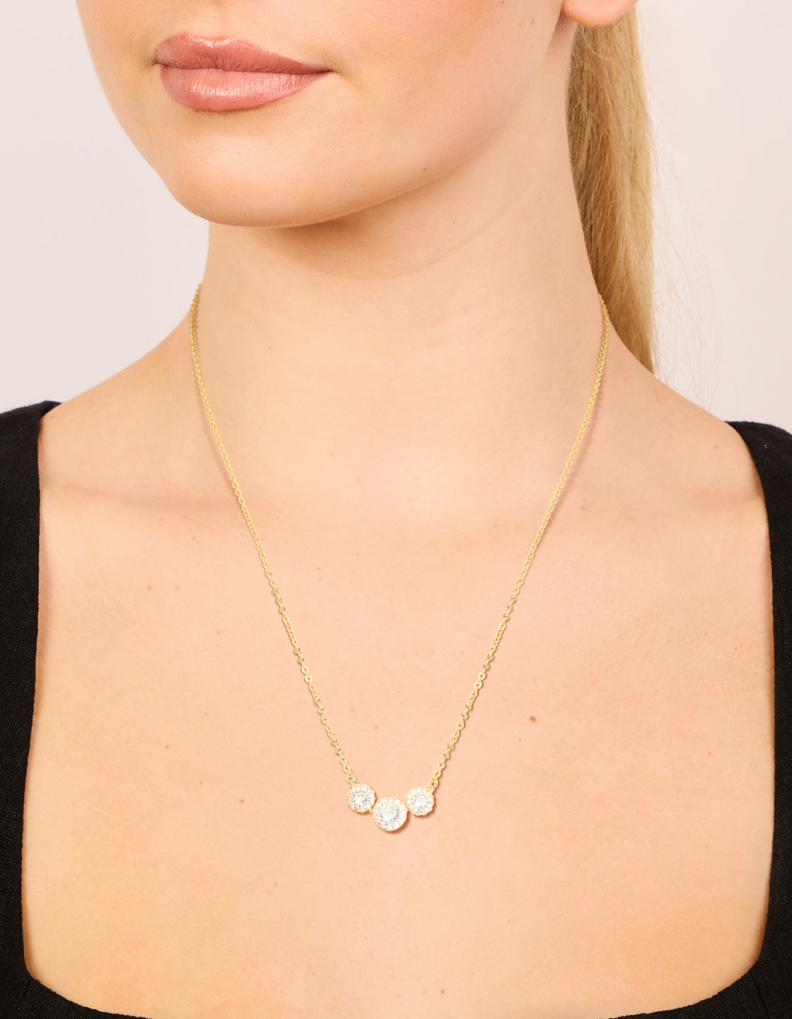 A gold plated cubic zirconia featuring trio halo stone cut necklace on neck view