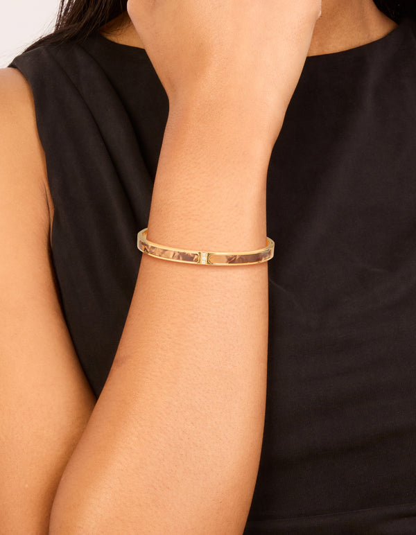 Showcasing a waterproof gold plated stainless steel hinged bangle with brown pearlised inlay on wrist view
