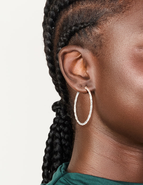 Showcasing textured surgical steel hoop earrings in silver 40 MM worn on ear view