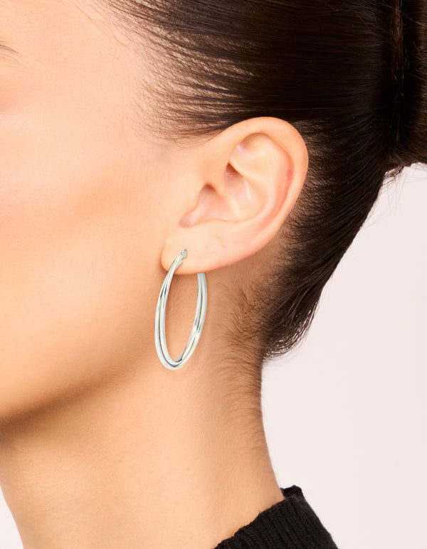 Showcasing surgical steel crossover hoop earrings in silver 40 MM on ear view