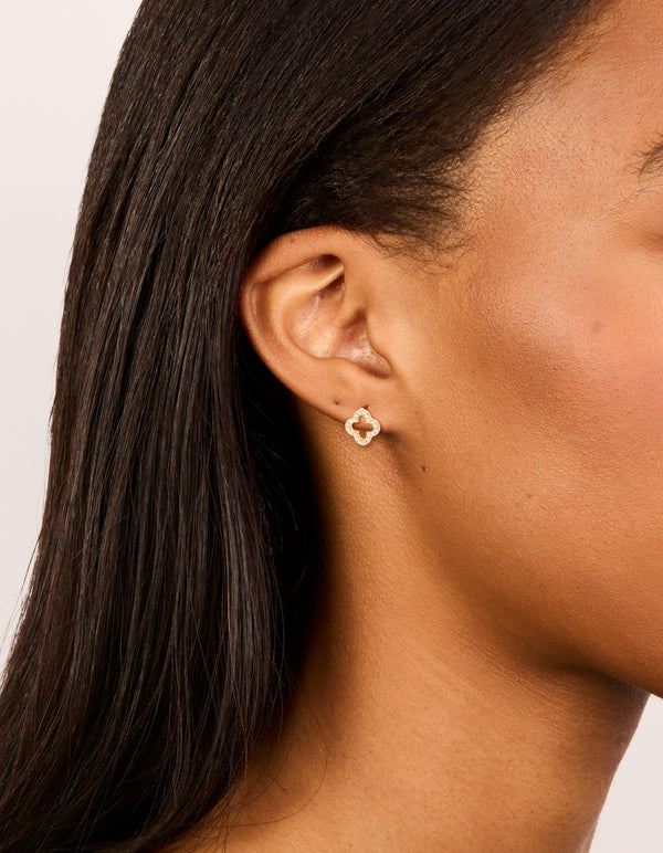 Featuring waterproof gold plated stainless steel cubic zirconia outline flower stud earrings highlighting floral detail on ear view