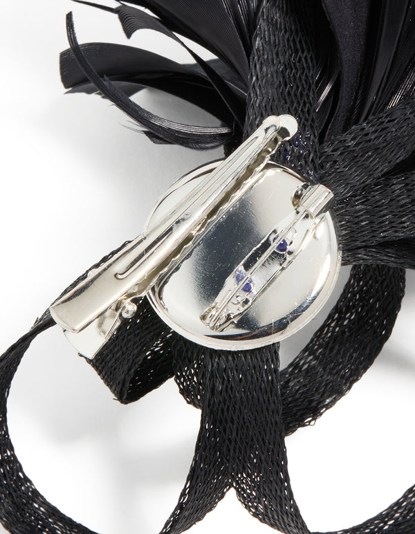 Crafted black loop feather hair clip with silver closure mechanism detail view