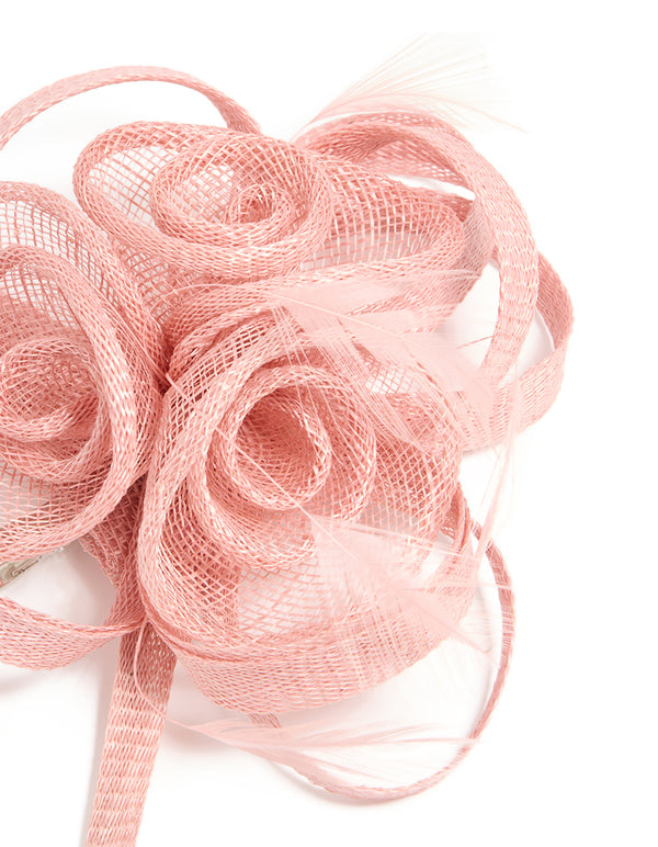 Featuring a sinamay fabric swirl hair clip with feathers and floral accents in light pink detail view