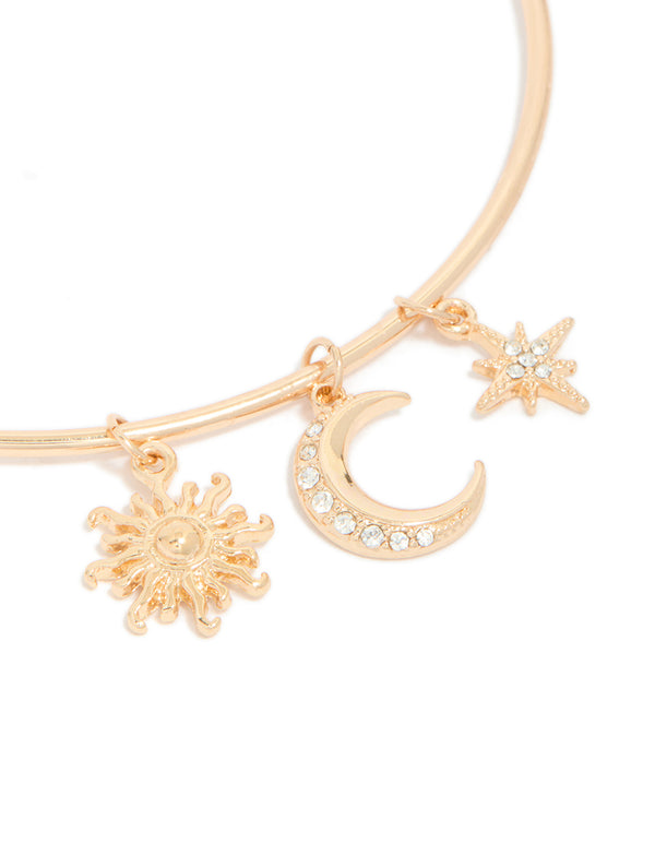Crafted from gold with celestial charms featuring sun, moon, and star in statement style in close up view