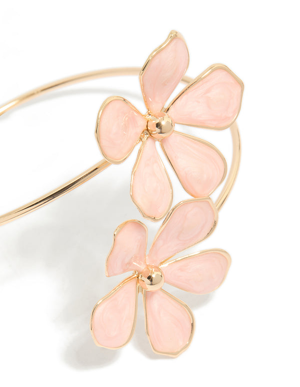 Crafted from enamel, this statement arm cuff with light pink floral design in gold close up view
