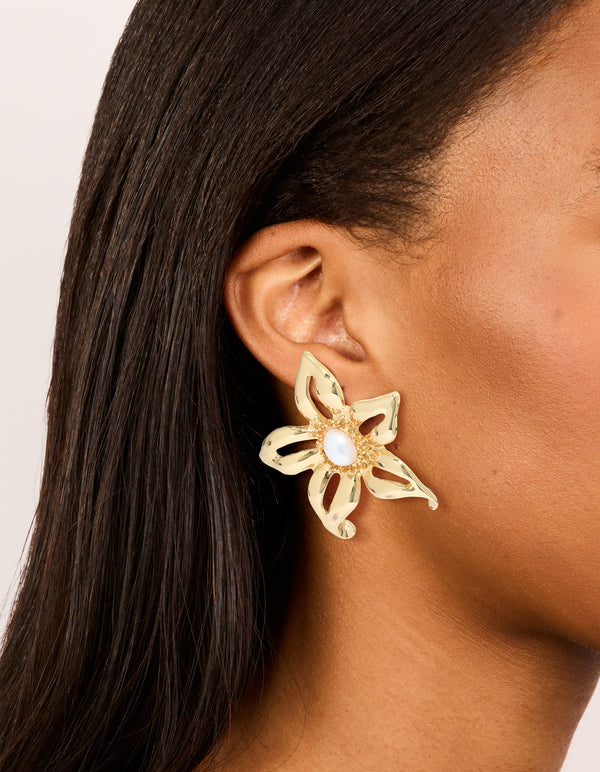 Showcasing gold plated statement pearl flower earrings on ear view