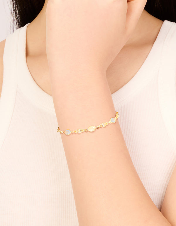 Beautifully showcasing a gold plated blue and beige oval cubic zirconia toggle bracelet on wrist view