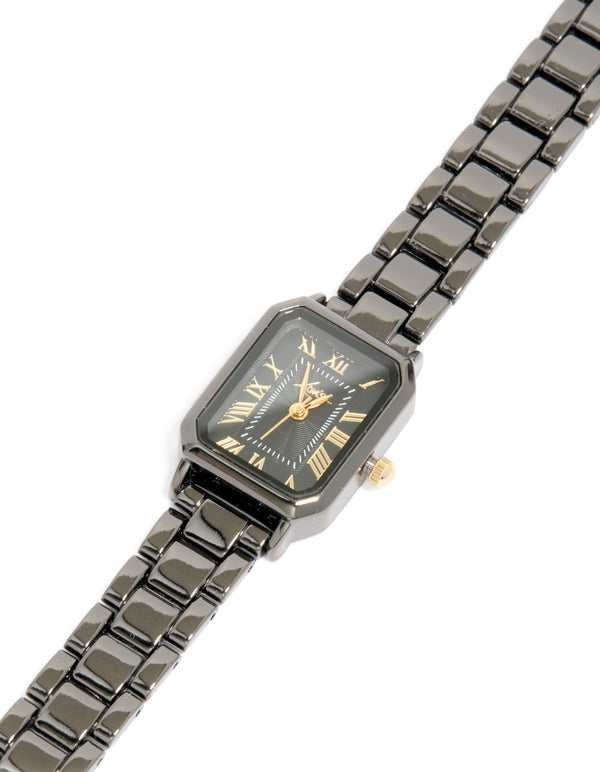 Featuring a black coated metal rectangle roman numeral watch with gold numerals, analog display, link band, and formal styling watch face detail view