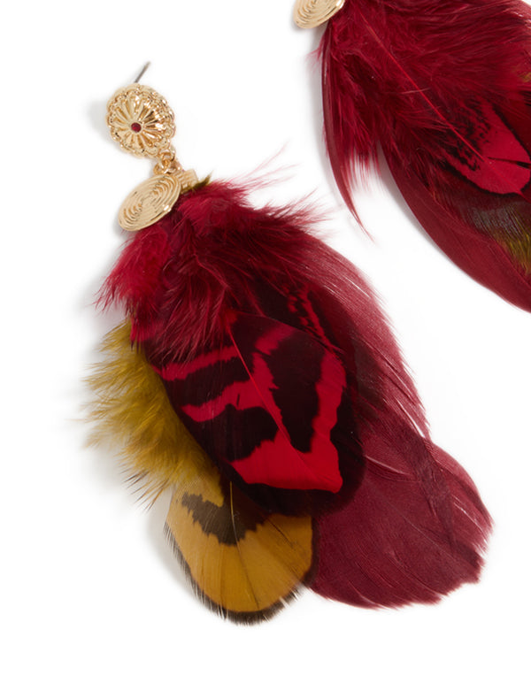 Highlighting gold, hot pink and yellow feather drop earrings with statement style and textured details close up view