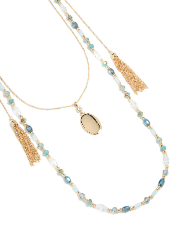 Discover this layered necklace with blue beads, tassel and oval pendant in statement styling in gold close up view