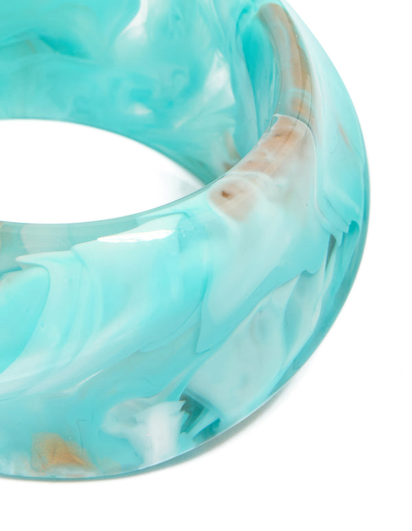 Showcasing a light turquoise and tan marbled acrylic statement bangle with chunky design close up view