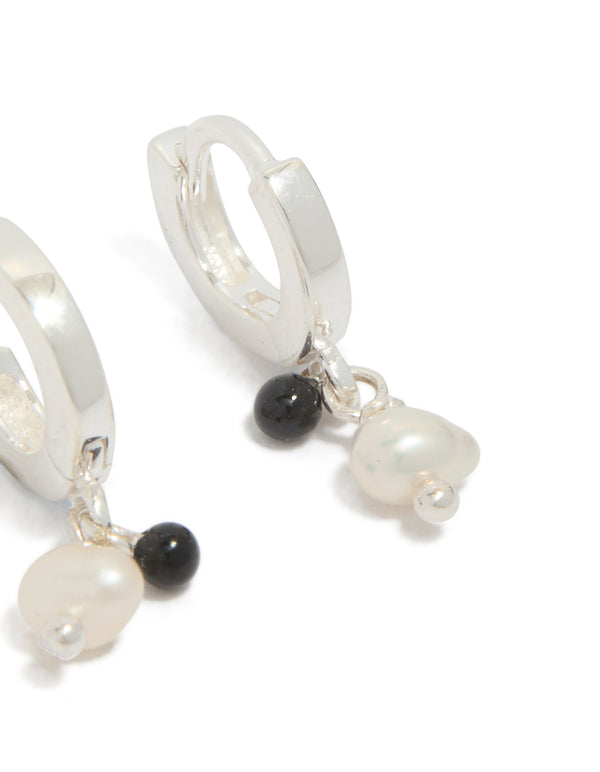 Showcasing sterling silver drop huggie earrings with beaded charm featuring pearl and black stone post detail view