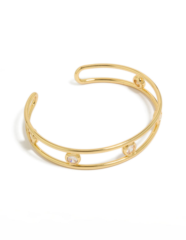 Crafted from gold plated brass, this statement bangle features bezel set cubic zirconia stones in a wrist cuff design front view