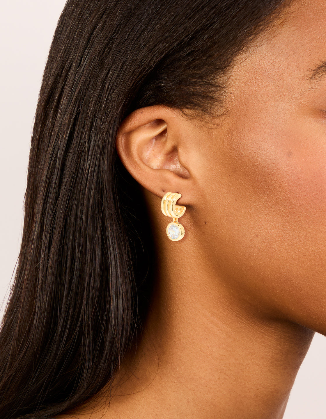 Beautifully crafted gold plated cubic zirconia bezel line huggie earrings on ear view