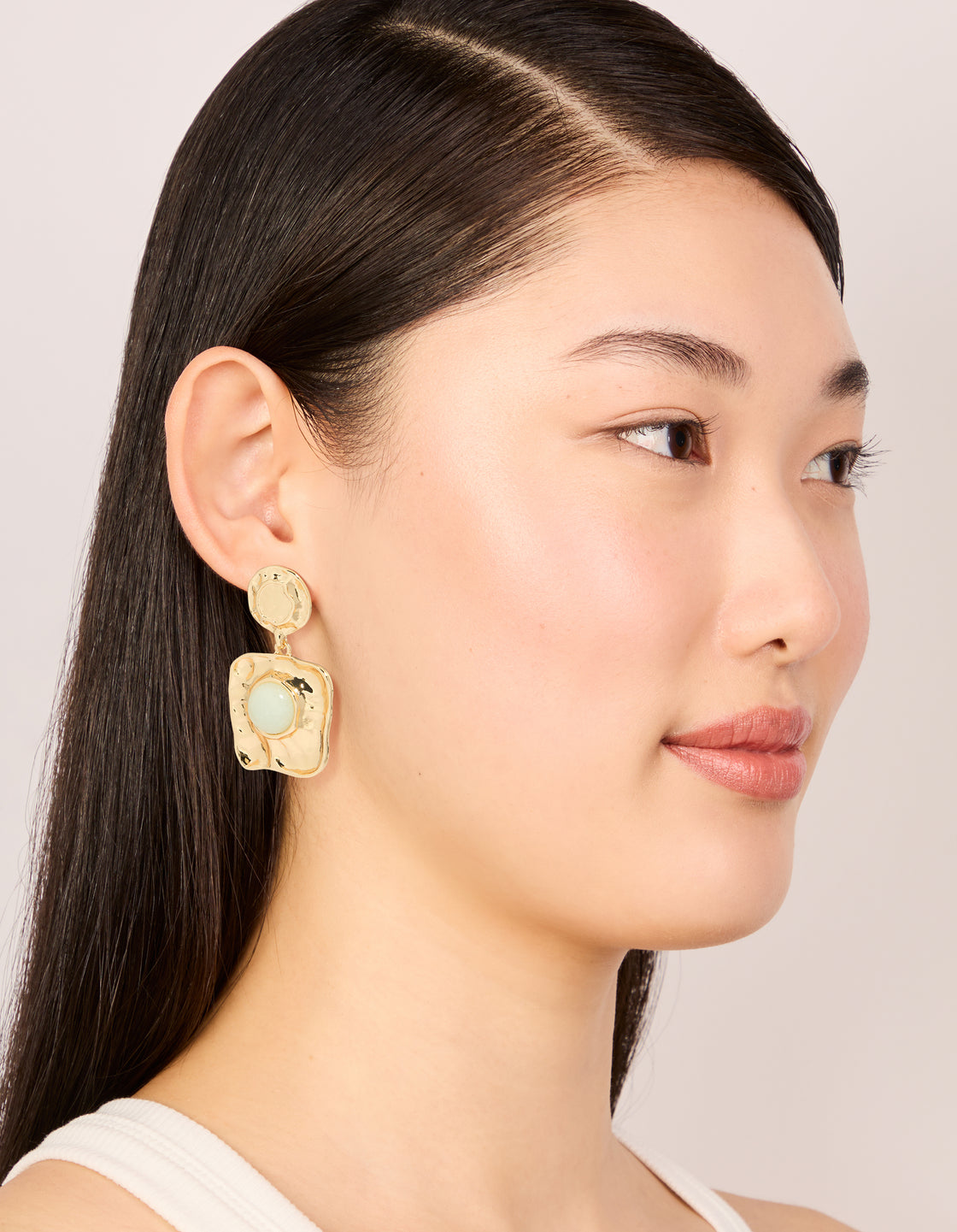 Highlighting statement drop earrings in gold with pale green stone and molten square design on model view