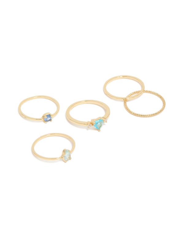 Showcasing a gold-plated stackable ring set featuring heart, round, and oval shaped blue cubic zirconia stones, front view