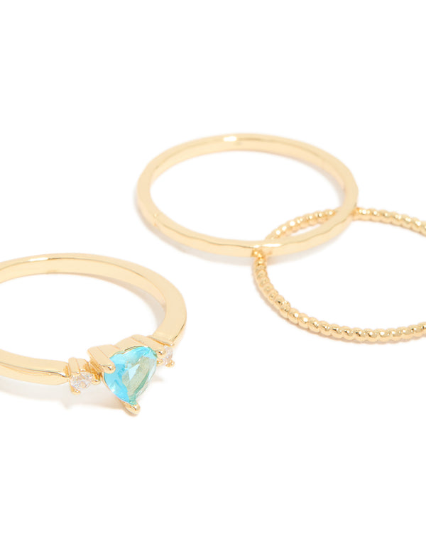 Highlighting gold-plated stackable ring set featuring heart, round, and oval shaped blue cubic zirconia stones bubble texture side detail view