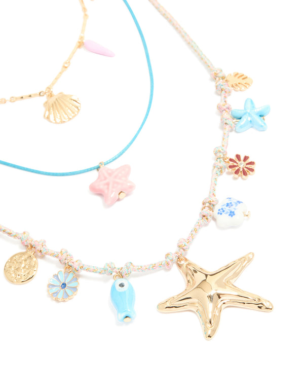 Showcasing gold blue cord sea charm layered necklace featuring floral, leaf, ocean and coin close up view