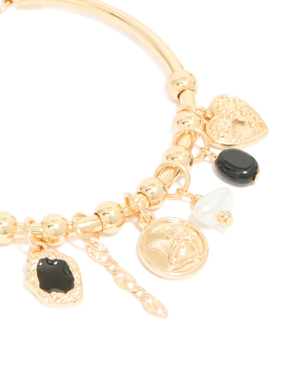 A gold heart and black stone charm bracelet designed with balls, coin and pearl elements close up view